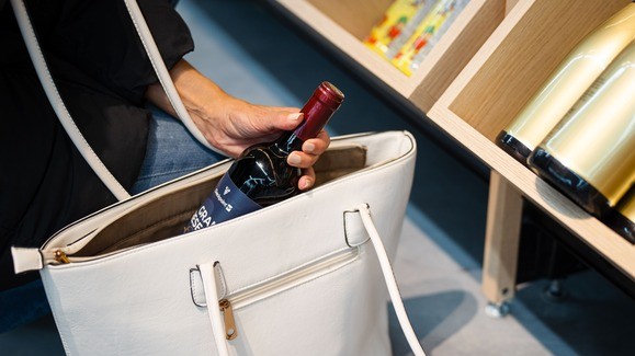 Alguien introduce una bottella de vino en un bolso