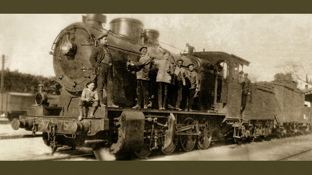 Un grupo de maquinistas y ferroviarios posan con orgullo sobre una imponente locomotora de vapor de principios del siglo XX