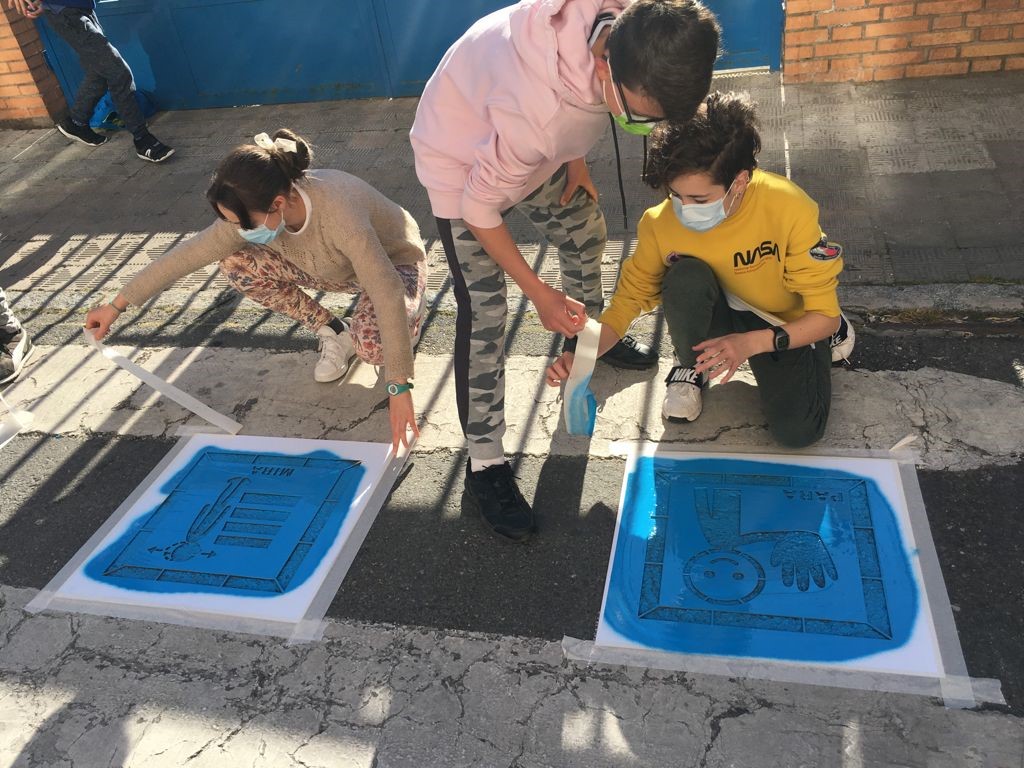 Niños pintan pictogramas en un paso de cebra.