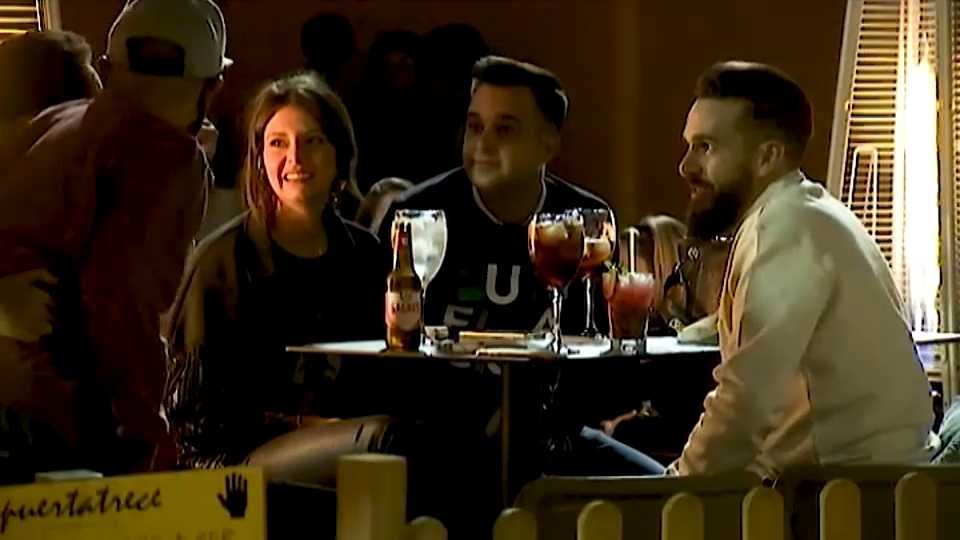 Jóvenes tomando una bebida en la terraza de un bar de noche
