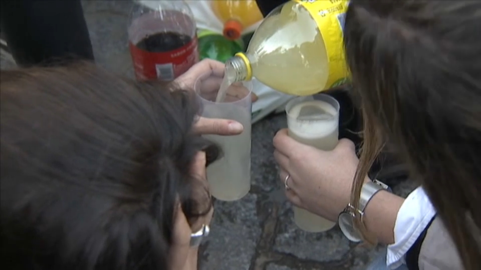Varios jóvenes echan alcohol en vasos durante un botellón