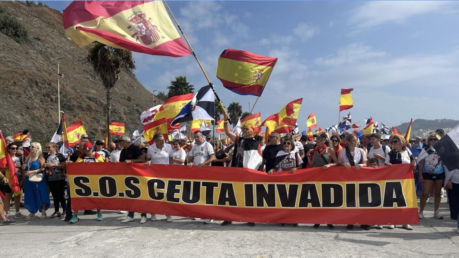 Cientos de ceutíes portan una pancarta con el lema 'SOS Ceuta invadida' durante una manifestación en defensa de la españolidad de la ciudad y de su frontera, a 20 de septiembre de 2026, en Ceuta (España).